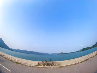 A bicycle sits on the side of the road with a stunning view of the water and mountains in the distance