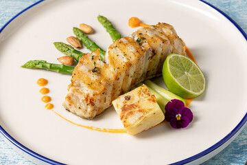Gourmet grilled white grouper fillet served with asparagus, almond, and lime