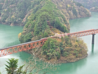 The bridge spans the water, connecting two land masses with vibrant foliage and a cloudy sky overhead