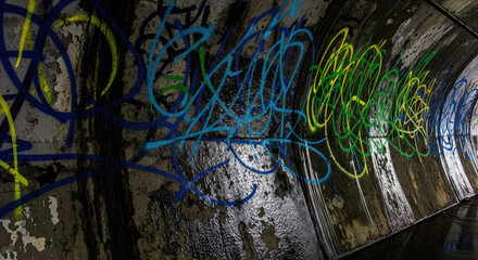 Vibrant spray paint graffiti on textured concrete tunnel wall, urban street art