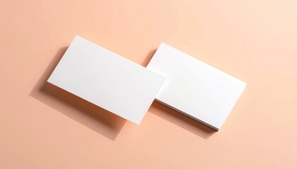 Two stacks of white, rectangular paper rests diagonally on a peach background with soft shadows on one side