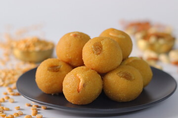 Chana dal motichur laddus stacked on a black plate, garnished with dry fruits