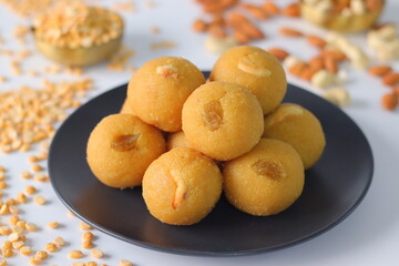 Chana dal motichur laddus stacked on a black plate, garnished with dry fruits