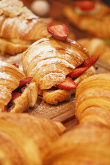 Freshly baked croissants with strawberries on a wooden tray
