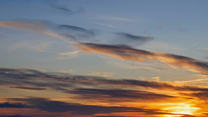 Sunset colors on a calm horizon with thin clouds creating a dramatic sky
