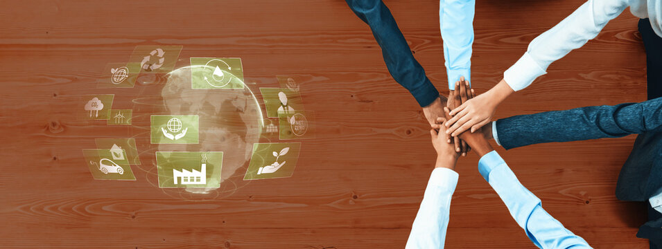 Diverse hands come together on a wooden surface, symbolizing unity and collaboration. Digital icons highlight eco-friendly practices and sustainable development efforts. Trope - Powered by Adobe