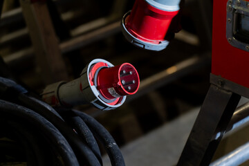 Industrial electrical connector with red casing and multi pin arrangement aligned near thick cable, highlighting robust construction and professional grade power distribution hardware