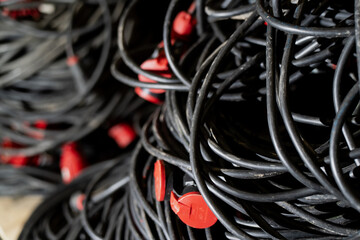 Massive collection of looped power cables stacked in dense piles with red end caps, illustrating heavy duty wiring storage, equipment organization and field distribution potential