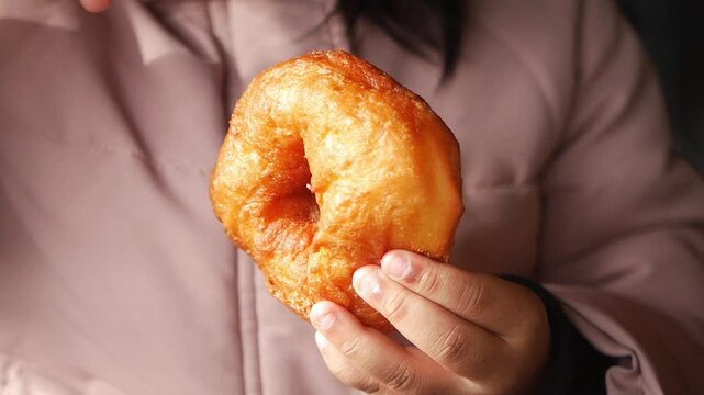 A child holds a warm, golden pastry, highlighting its texture and shape