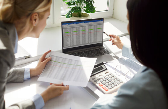 Business people or colleagues working together in office with laptop and documents during meeting, focusing on online teamwork in a professional setting with collaboration and engagement.