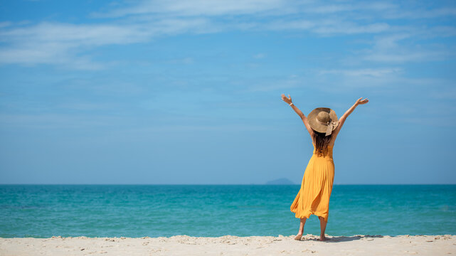 Summer vacations. Lifestyle woman relax and chill on beach background.  Asia happy young people wearing yellow dress fashion summer trips walking enjoy  tropical beach. Lifestyle and Travel Concept