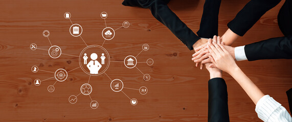 A group of diverse hands comes together on a wooden table, showcasing teamwork and collaboration, surrounded by digital icons symbolizing growth and connectivity. Trope