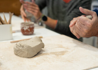 Hands molding clay during a pottery workshop