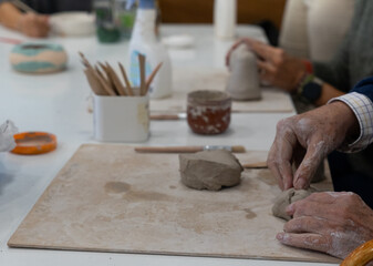 Senior hands shaping clay during pottery workshop