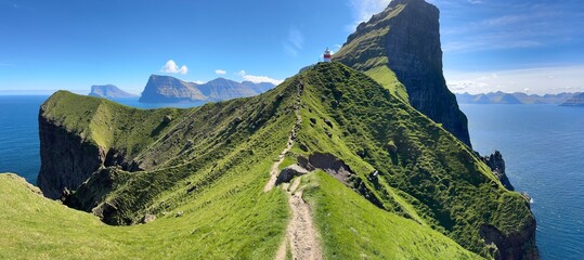 Panorama. Kallur lighthouse on green hills of Kalsoy island on sunset time, Faroe islands, Denmark. Landscape photography