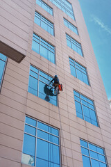 Rappelling Window Cleaner Working On High Rise Building With Safety Gear