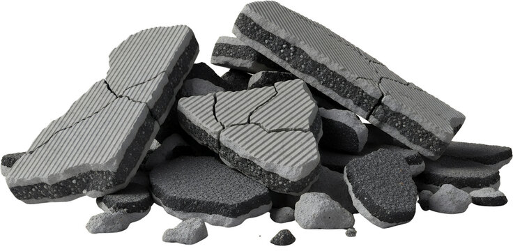 Pile of broken asphalt road pieces showing grey concrete top layer with lines and black tar bottom layer debris construction