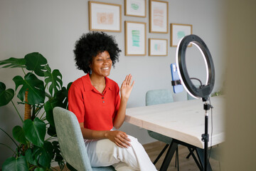Black woman vlogging content from home office with ring light