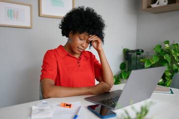 Stressed woman experiencing headache working from home on laptop