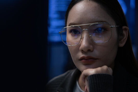 Asian Focused programmer night office blue light computer screen reflection glasses Asian woman serious coding cybersecurity