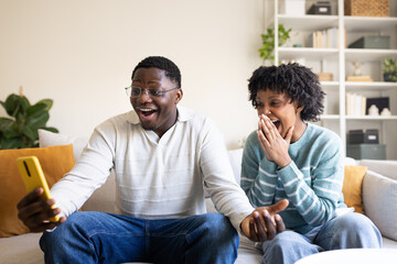 Excited couple reacting to unexpected news on smartphone at home