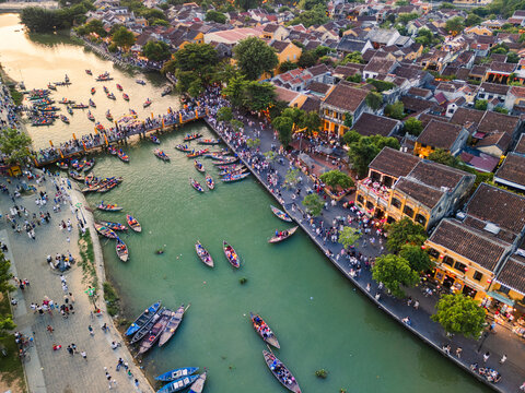 Drone View of Hoi An Riverside With Lantern Boats and Crowds at Sunset - Powered by Adobe