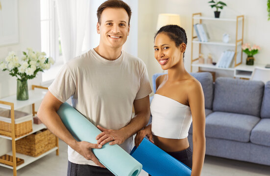 Couple family practicing home fitness together. Smiling partners hold yoga mats for workout, fit training, exercise, wellness and lifestyle. Wellness, sport and healthy lifestyle concept.