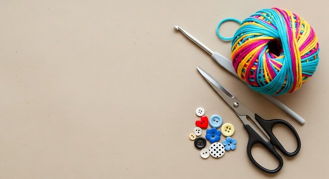 Colorful yarn ball, crochet hook, scissors and buttons on beige surface knitting craft
