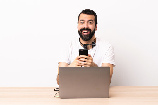 Telemarketer caucasian man working with a headset and with laptop surprised and sending a message.