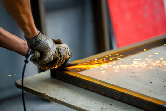 Grinding machine at work. Sparks fly from under the grinders, men's work. Dark background with copy space.
