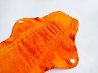 orange reusable menstrual cloth pad on a white background
