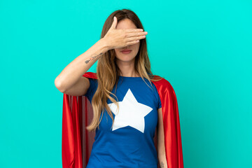 Super Hero caucasian woman isolated on blue background covering eyes by hands. Do not want to see something