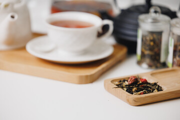 Herbal tea scene, warm cup and loose leaves on wooden trays