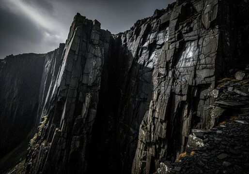Dramatic dark slate cliff face revealing jagged texture under moody sky - Powered by Adobe