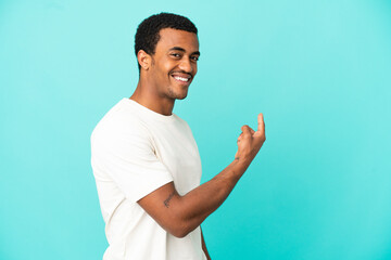 African American handsome man on isolated blue background pointing back