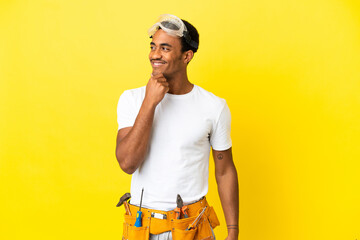 African American electrician man over isolated yellow wall looking to the side and smiling