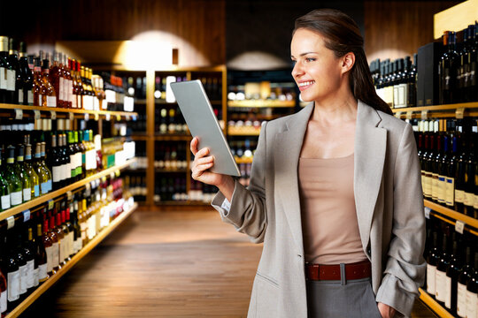 Female professional using digital tablet on background of wine shop.
