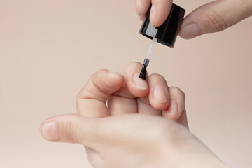 Manicure with colorless protective varnish. Woman paints her nails. Nude background copy space photo close up