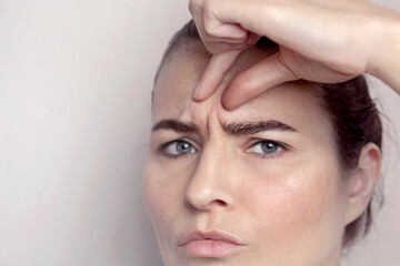 Glabellar lines, folds in a middle-aged woman with blue eyes. Copy space
