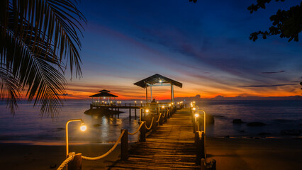 Stunning sunset at Koh Kood Island with a charming wooden pier illuminated by soft lights