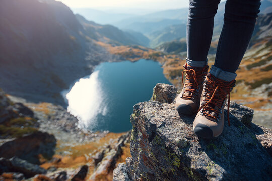 Hikers boots perched on a rocky cliff overlooking a vast mountain landscape and reflective lake