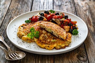 Vegetable pancakes with fresh salad on wooden table