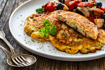 Vegetable pancakes with fresh salad on wooden table