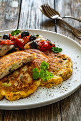 Vegetable pancakes with fresh salad on wooden table