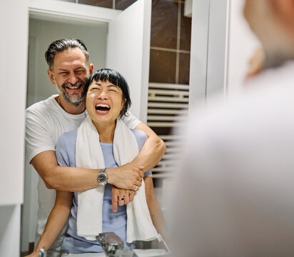 Portrait of a young couple applying cream, skincare and cosmetic,  in front of mirror in bathroom. Dental hygiene, youth, love and beauty concepts