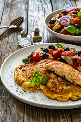 Vegetable pancakes with fresh salad on wooden table