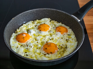 Feta fried eggs in frying pan on electric stove
