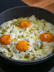 Feta fried eggs in frying pan on electric stove