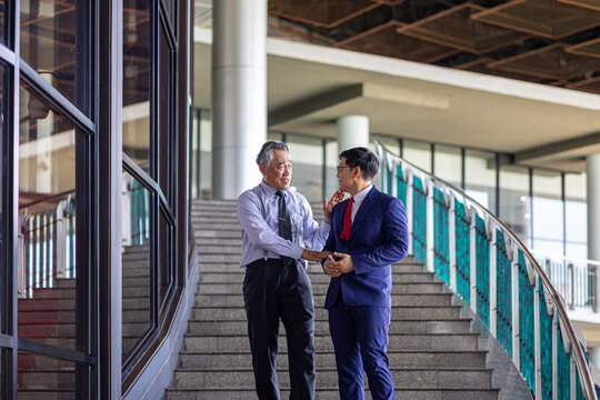 Meeting of two generations between senior and young business men at the company stairways sharing vision for their business development. Diversity and social inclusion in a business entrepreneurship