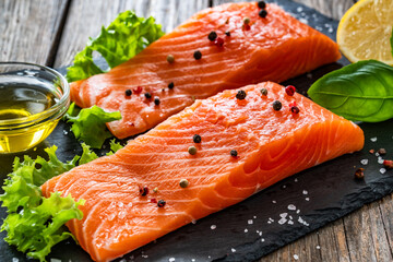 Fresh raw salmon steaks on black stony board on wooden background
